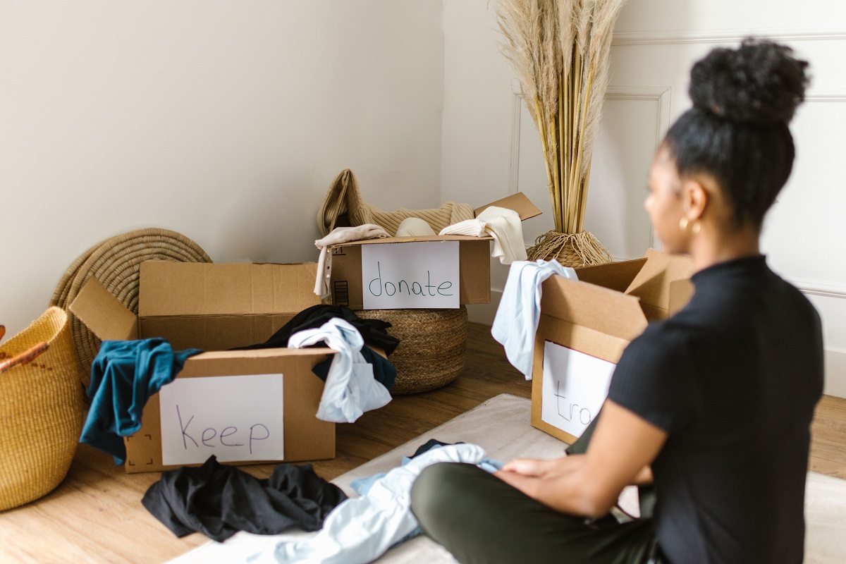 woman decluttering, with boxes labeled 'keep' and 'donate' around her