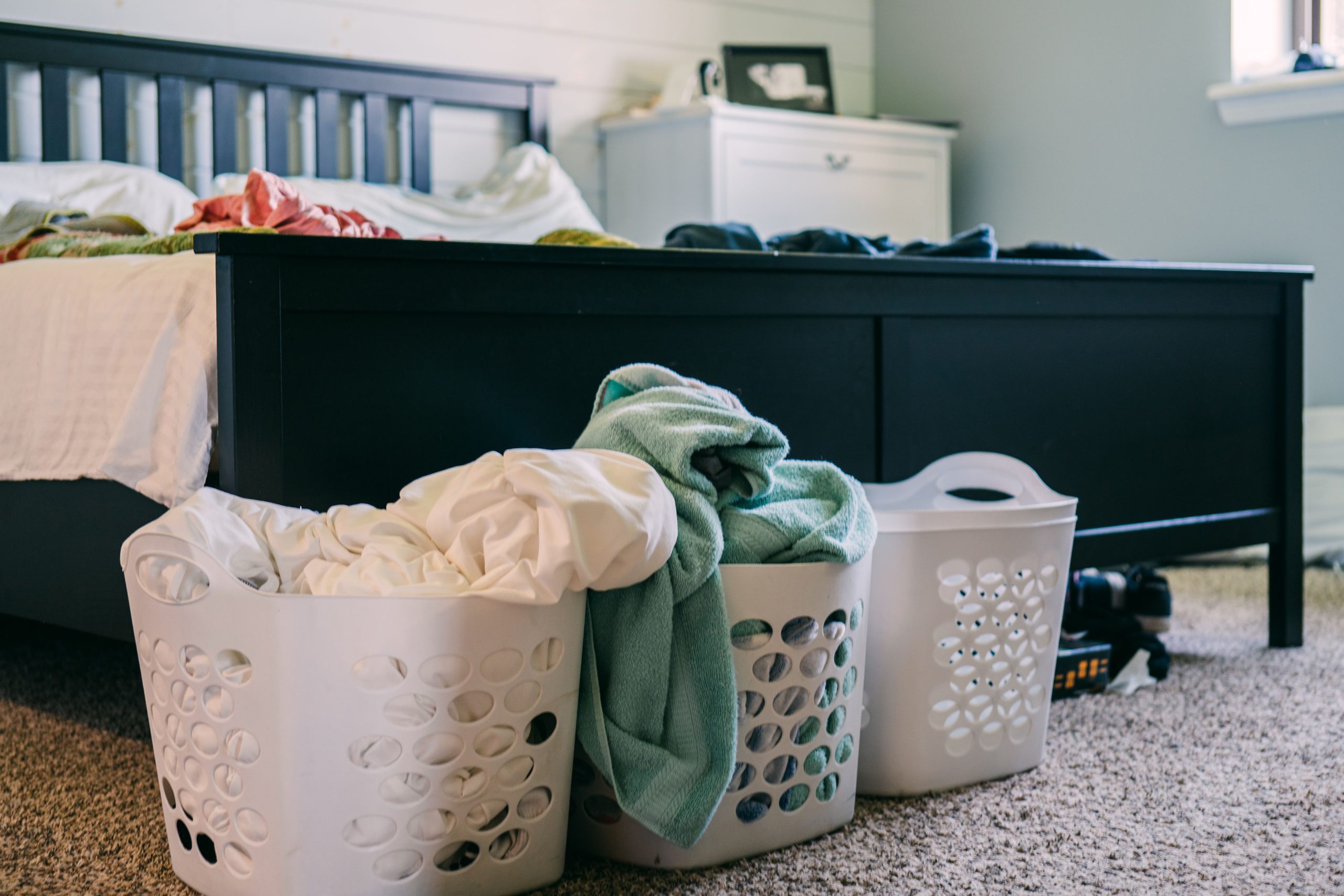 three baskets with clothes and sheets in a bedroom